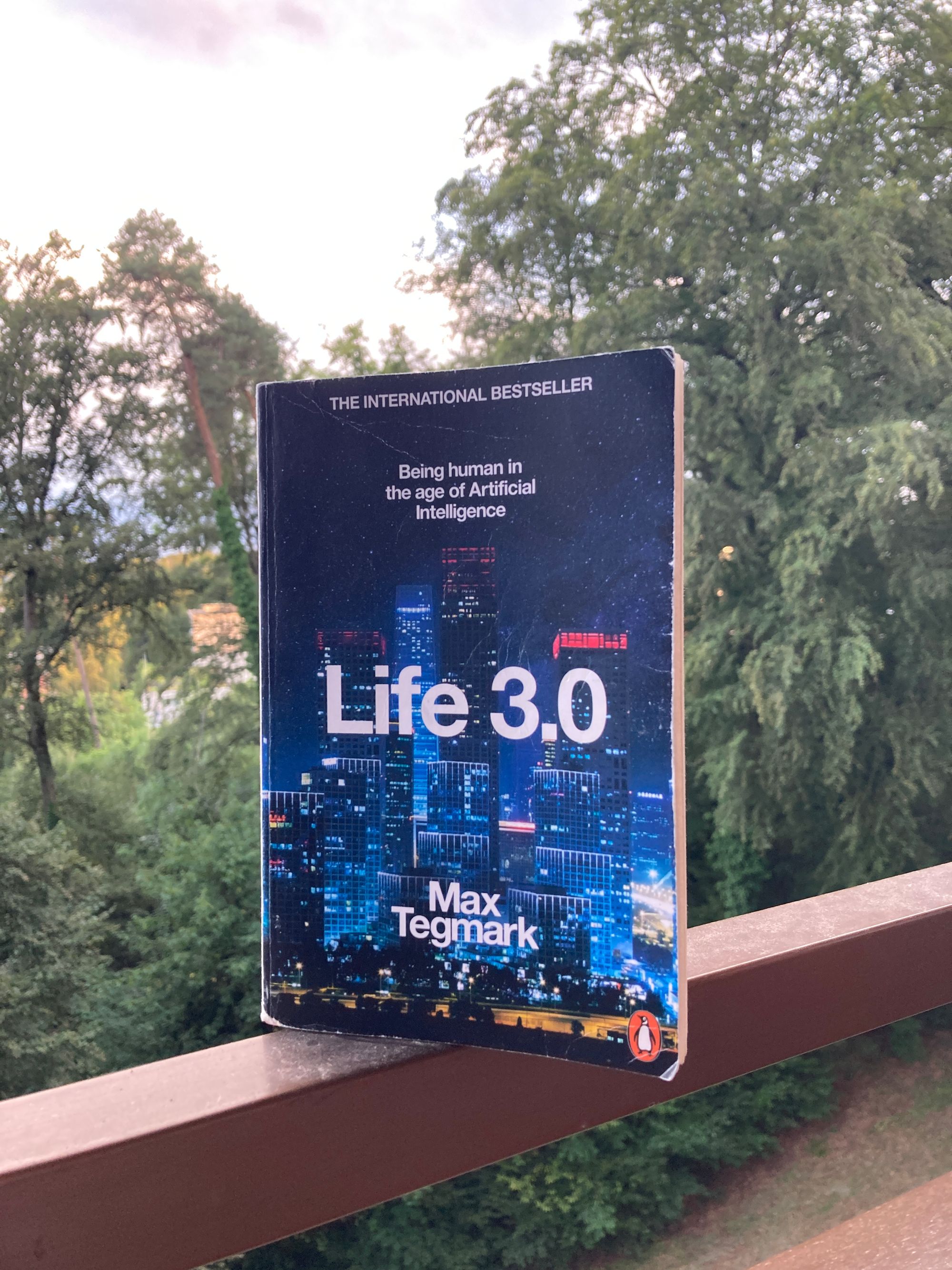 The cover of the book "Life 3.0" against a background of trees.