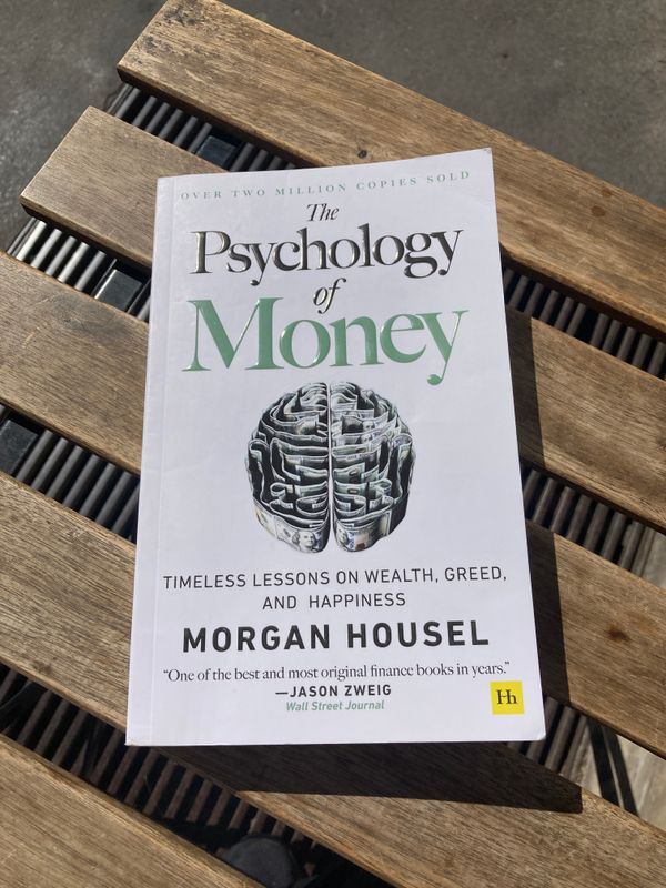 The book "The Psychology of Money" on top of a wooden table.