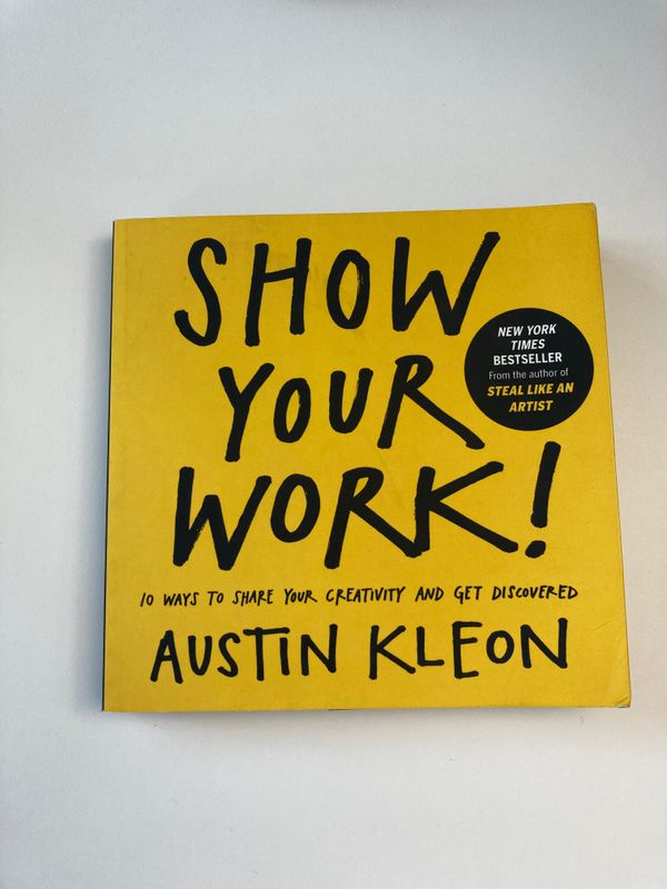 A picture of the book "Show Your Work!" by Austin Kleon on a white surface.